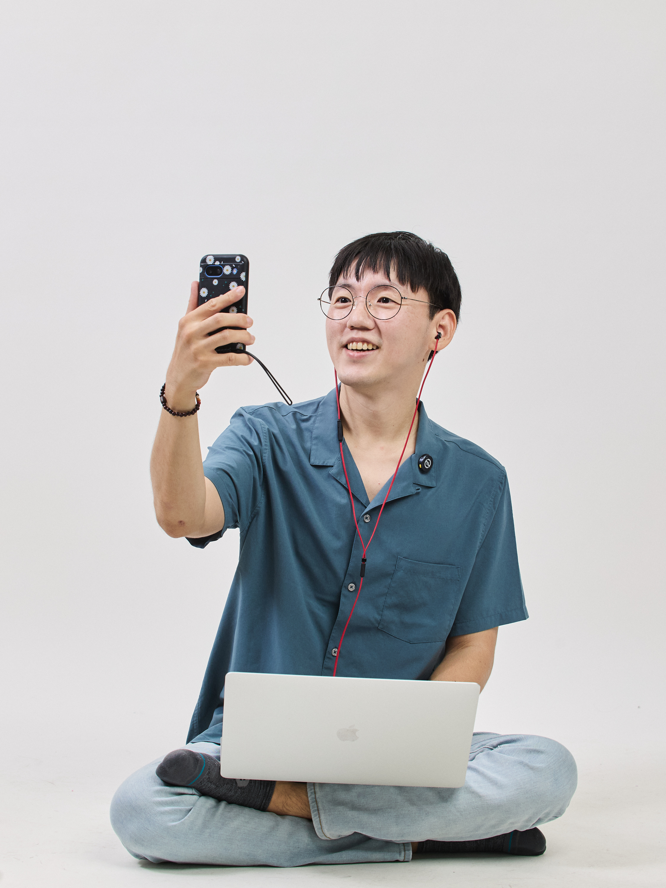 Billy Seol creating content — phone in hand, laptop open, fully engaged